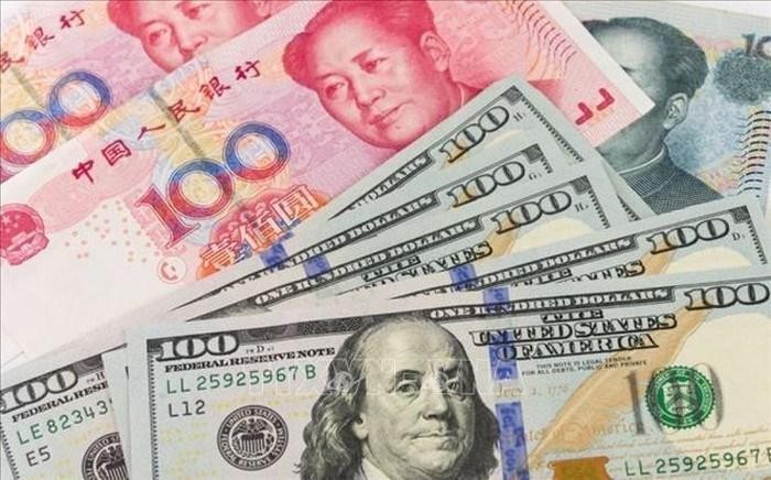 Đồng Nhân dân tệ (trên) và đồng đôla Mỹ. Ảnh: AFP/TTXVN